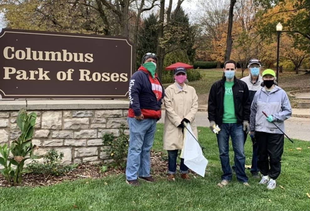 People wearing masks standing in from of "Columbus Park of Roses" sign.